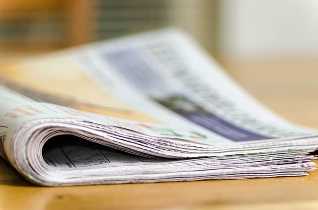 selective focus photography of a folded newspaper on a wooden table