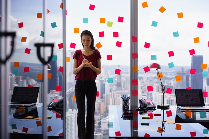 Busy-businesswoman-organizing-in-office-filled-with-sticky-notes Busy-businesswoman-organizing-in-office-filled-with-sticky-notes