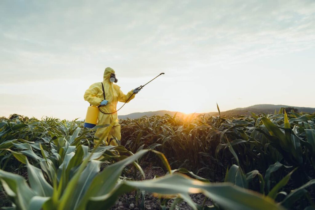 farmer in hazmat spraying fields with herbicde